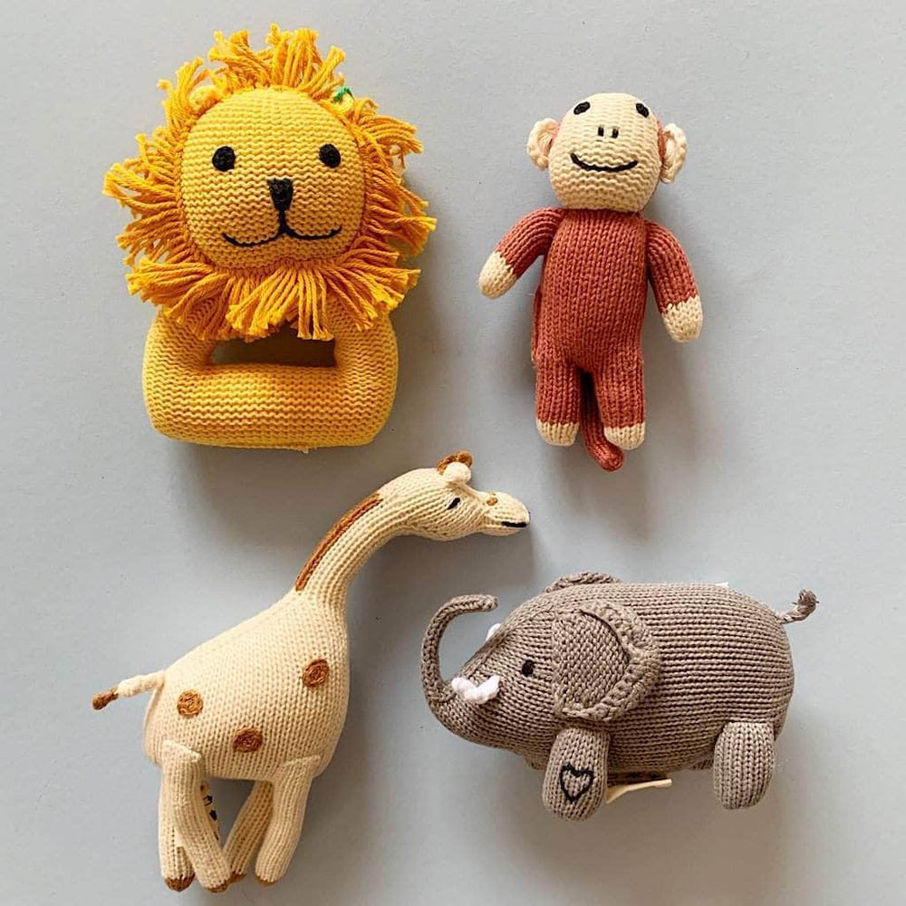 Set of four handmade knit safari animal toys, including a lion rattle, monkey plush, giraffe, and elephant, crafted from organic cotton for safe and eco-friendly baby play.
