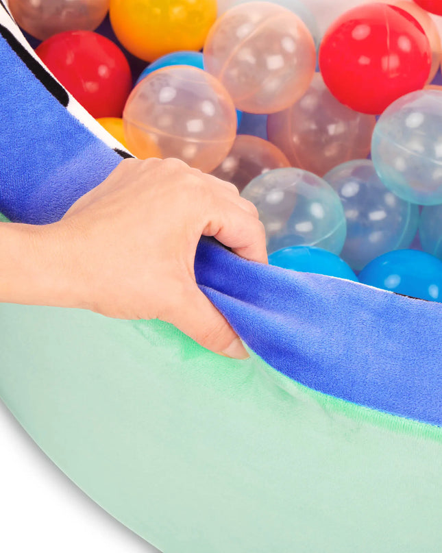 Colorful ball pit with a child's hand reaching in, surrounded by multicolored balls.