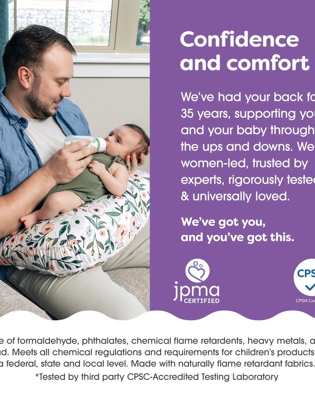 Man holding a baby in a floral baby carrier with text about confidence and comfort, JPMA certification, and CPSIA compliance.