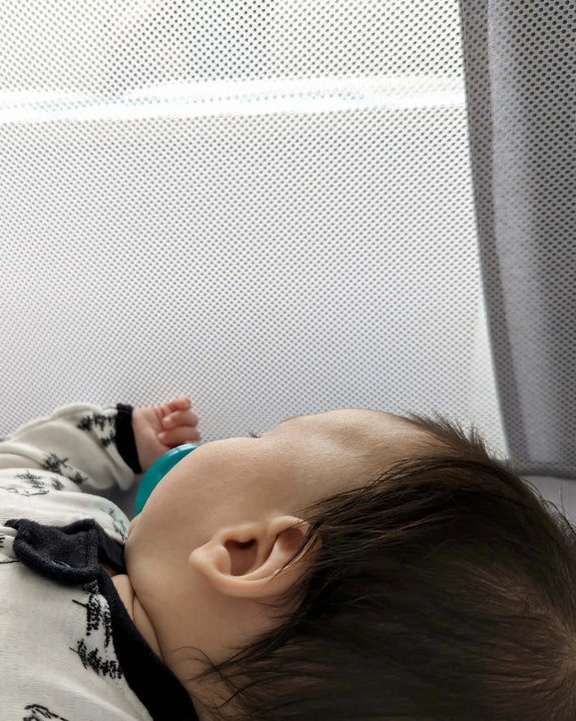 Baby lying on a surface with a textured white wall in the background