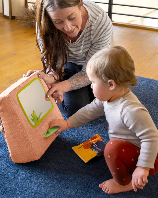Woman and child playing with a toy on a blue rug
