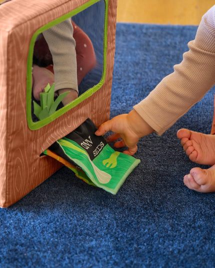 Child playing with a toy house on a blue carpet