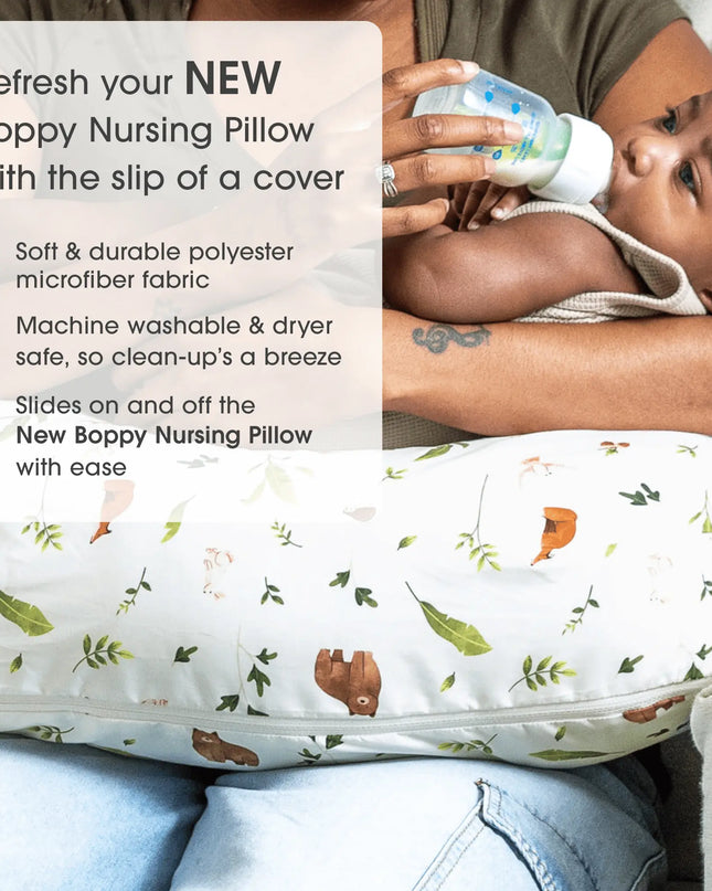 Person holding a baby and using a Boppy Nursing Pillow with a cover featuring animal prints.