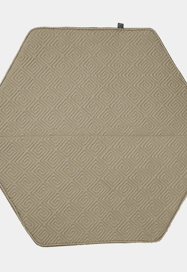 Hexagonal beige placemat with geometric pattern on a white background