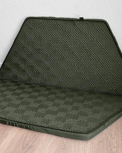 Green car seat cover with geometric pattern on a wooden floor.