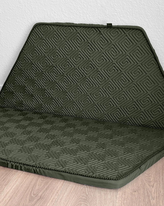 Green car seat cover with geometric pattern on a wooden floor.