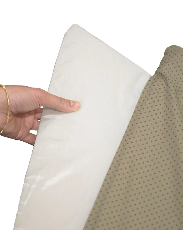 Hand holding a white pillow against a beige fabric background