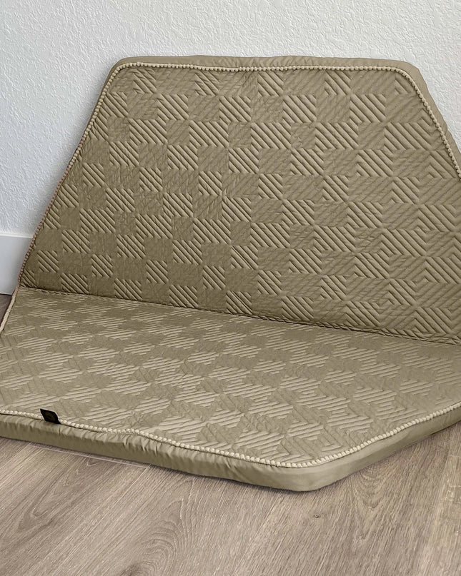 Beige quilted car seat cover on a wooden floor with a white wall background