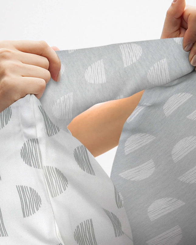 Person holding a piece of fabric with a pattern of gray shapes on a white background
