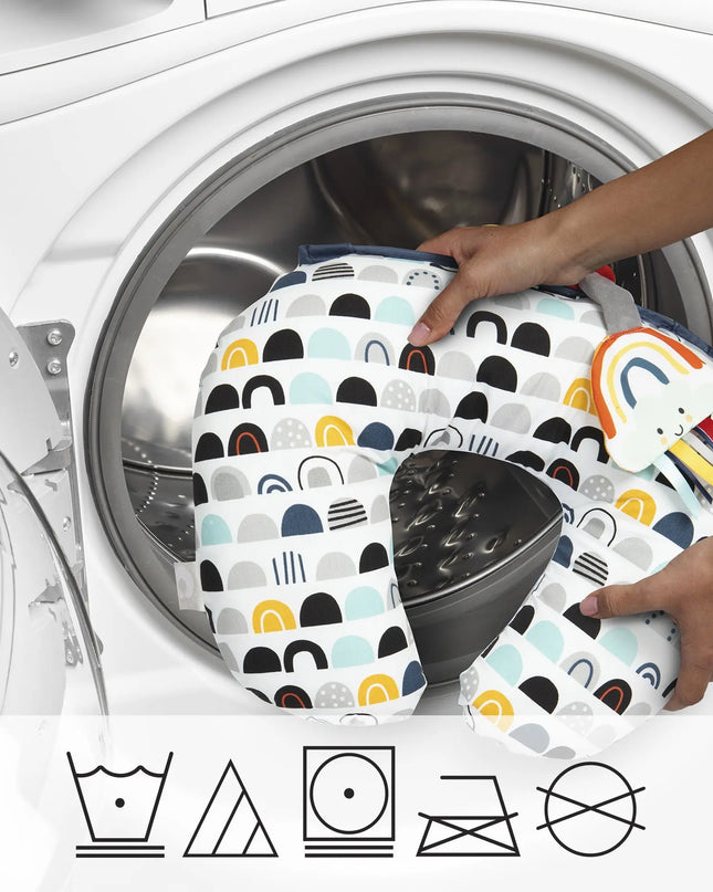 Person placing patterned fabric into a washing machine with laundry symbols below.