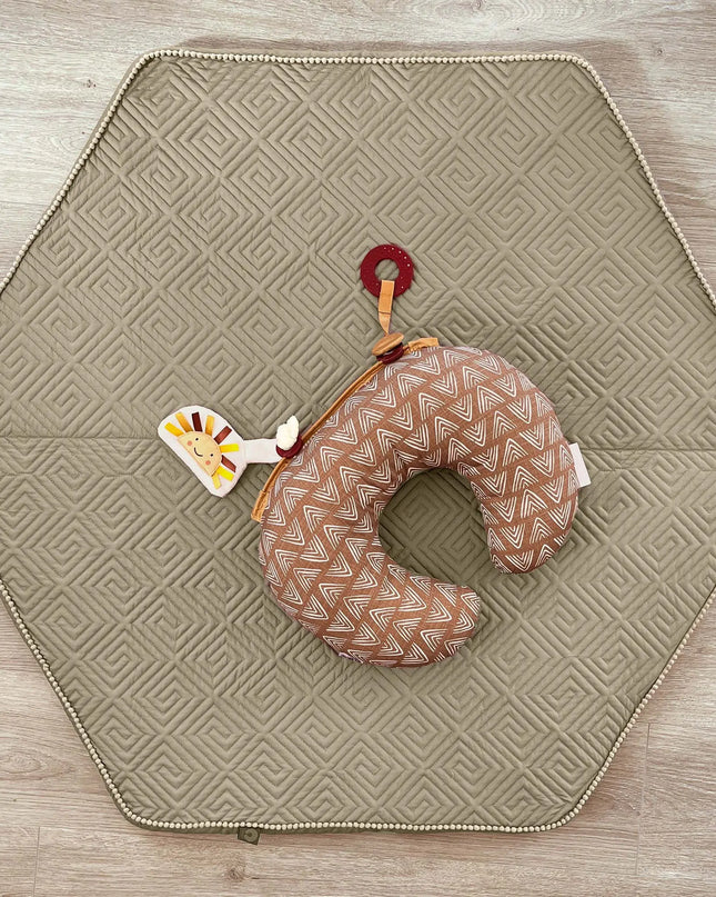 Hexagonal quilted mat with a neck pillow and toy on a wooden surface
