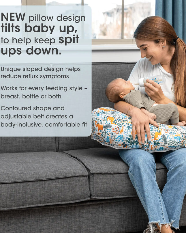 Woman feeding a baby using a pillow designed to help with spit-ups, sitting on a couch.