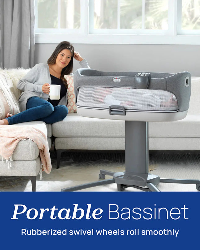 Woman sitting on a couch next to a portable bassinet in a living room.