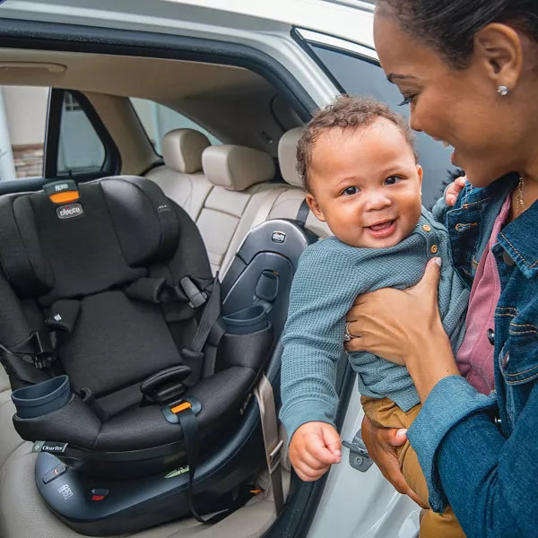 Woman holding a child next to a car seat in a vehicle
