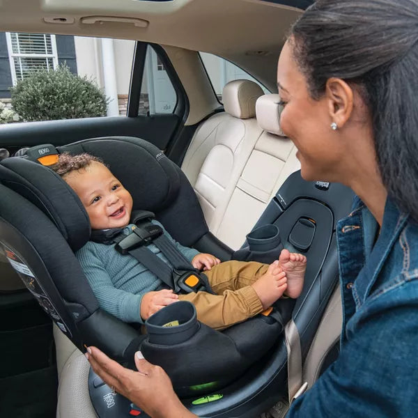 Woman adjusting a child in a car seat inside a vehicle