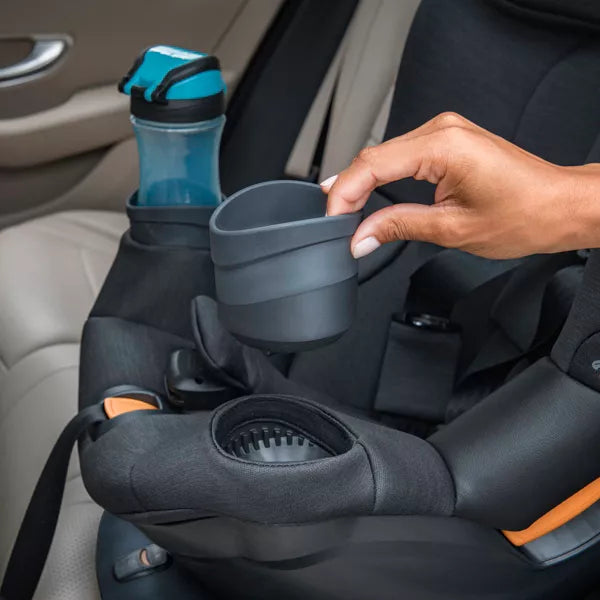 Collapsible cup being placed into a car seat cup holder with a water bottle beside it.