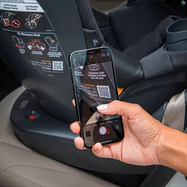 Person using a smartphone with a screen displaying QR codes in a car interior.