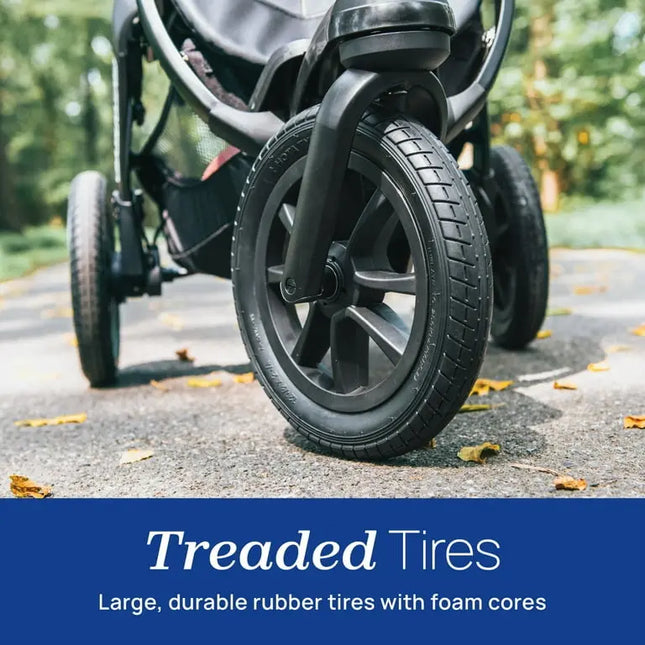 Close-up of a stroller wheel with treaded tires on a road, emphasizing durability.