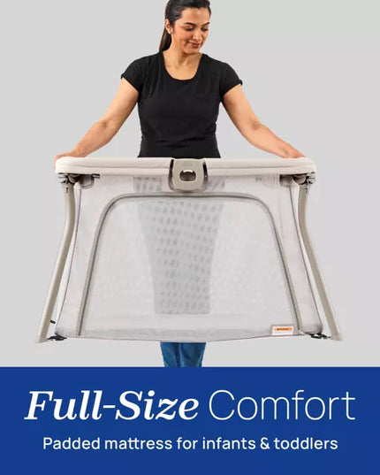 Woman holding a full-size comfort padded mattress for infants and toddlers against a gray background