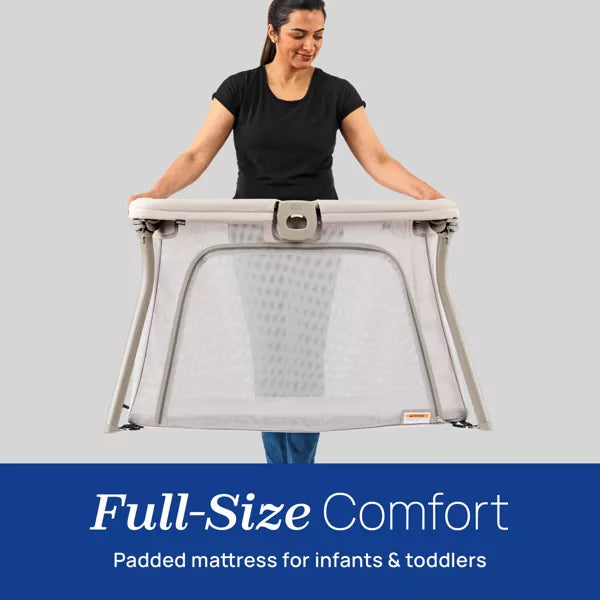 Woman holding a full-size comfort padded mattress for infants and toddlers against a gray background