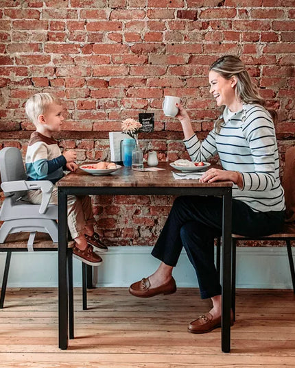 Woman and child sitting at a table with a brick wall background