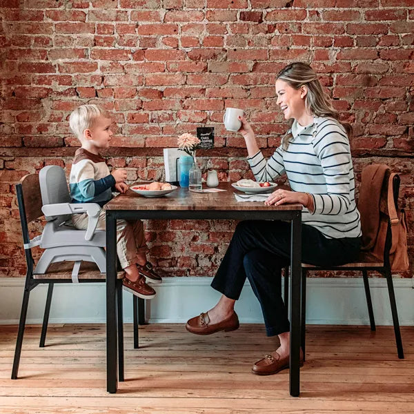 Woman and child sitting at a table with a brick wall background