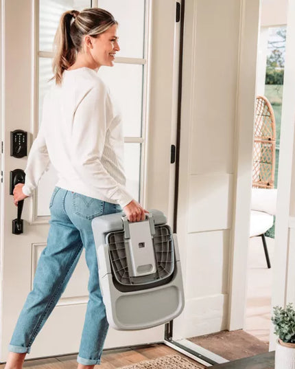 Woman carrying a pet carrier through a doorway in a home setting