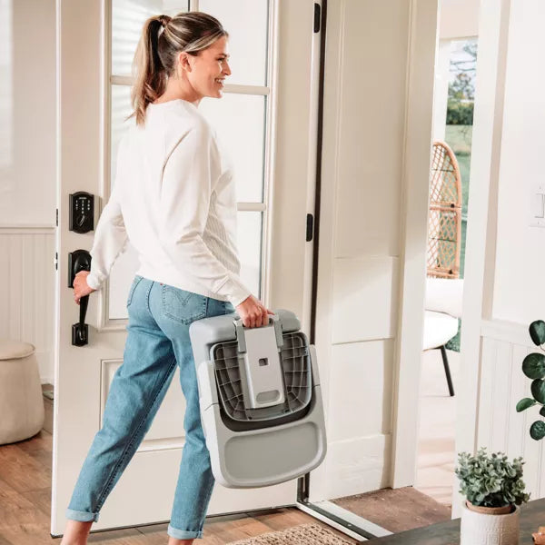 Woman carrying a pet carrier through a doorway in a home setting