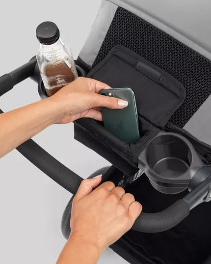 Person placing a phone into a stroller organizer with cup holder.