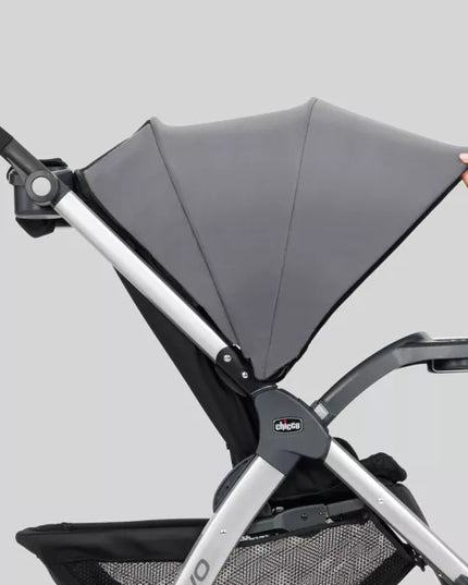 Gray stroller with a hand holding onto the canopy against a light gray background