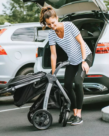 Woman pushing a stroller in front of an open car trunk
