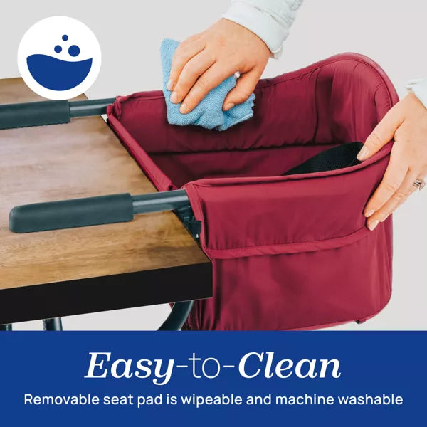 Person cleaning a maroon high chair with a blue cloth on a light gray background.
