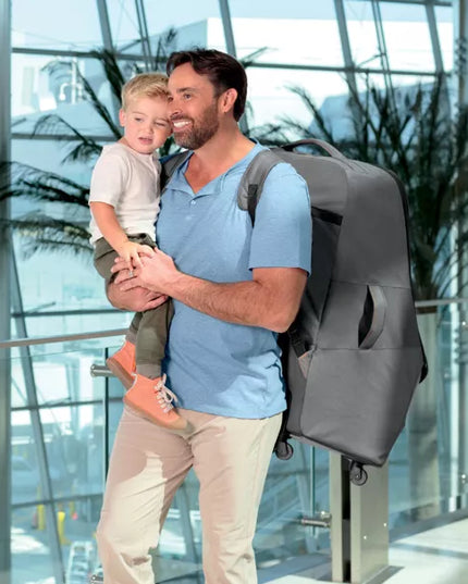 Man holding a child with a gray backpack in an indoor setting