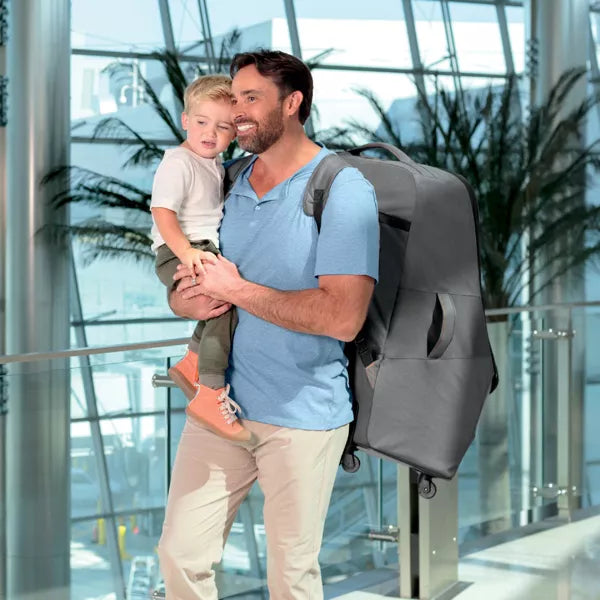 Man holding a child with a gray backpack in an indoor setting