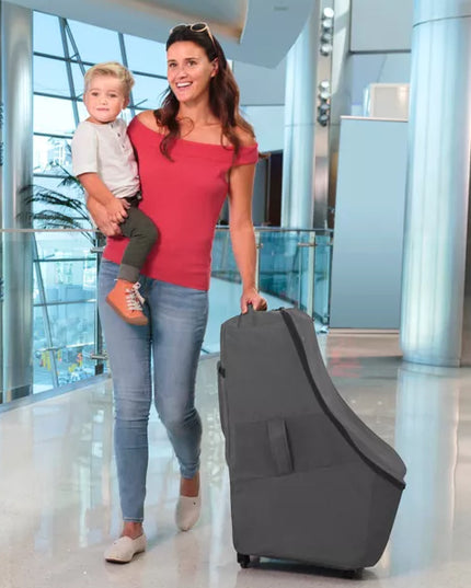 Woman holding a child and pulling a suitcase in an airport terminal