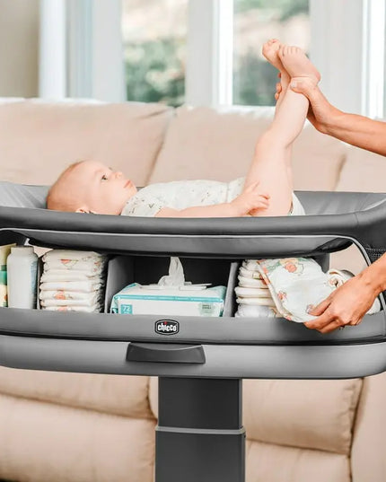 Baby changing table with baby and adult hands in a living room setting