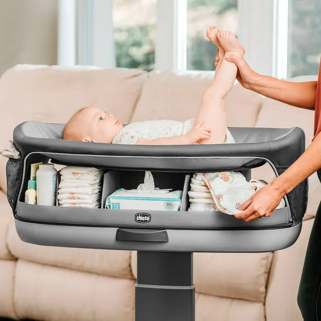 Baby changing table with baby and adult hands in a living room setting