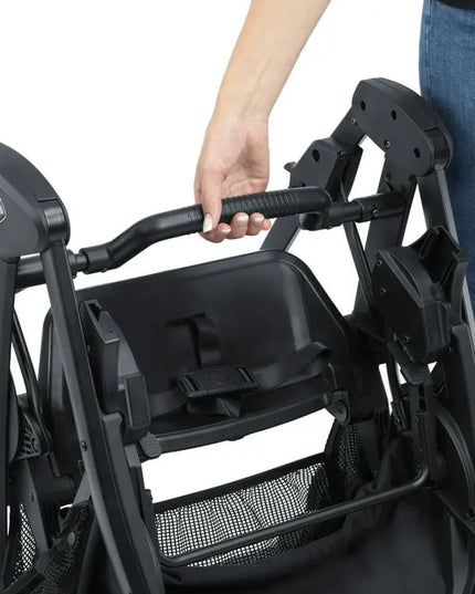 Close-up of a black stroller with a hand gripping the handle, on a white background.