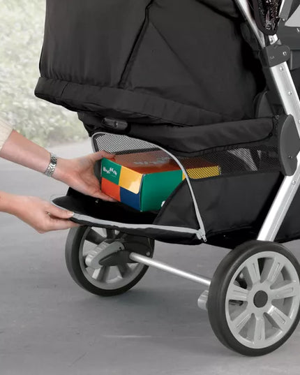 Person placing a colorful toy box into a black stroller.