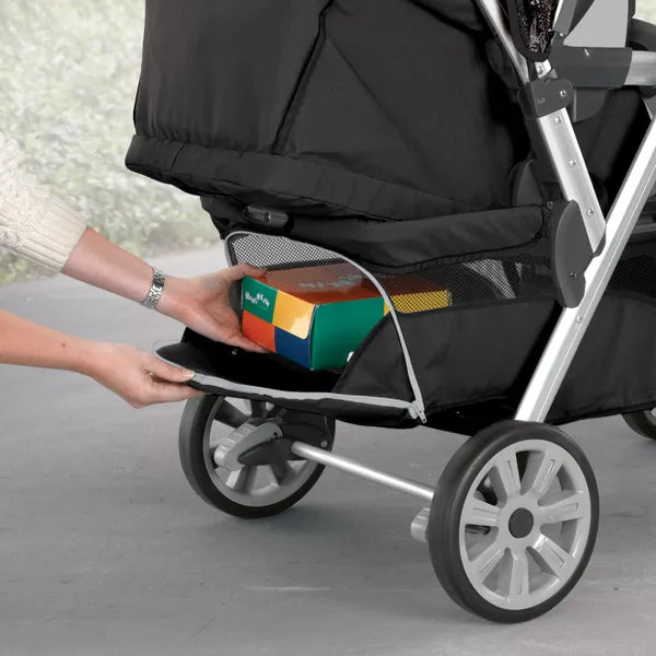 Person placing a colorful toy box into a black stroller.
