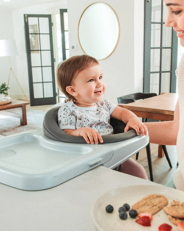 Child in a high chair with a woman in a modern kitchen setting