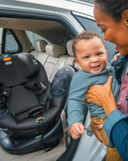 Woman holding a child next to a car seat in a vehicle