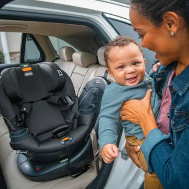 Woman holding a child next to a car seat in a vehicle