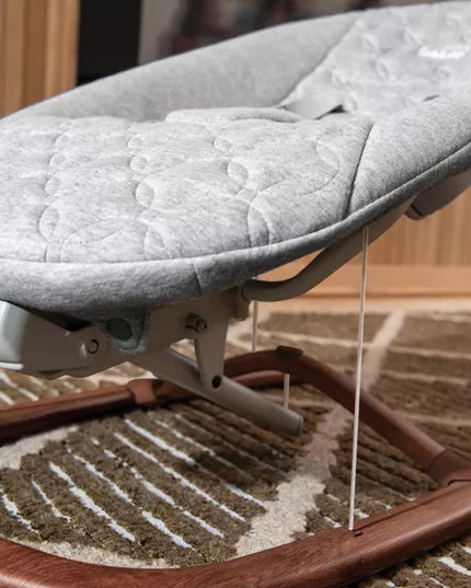 Baby bouncer with gray cushion on a carpeted floor