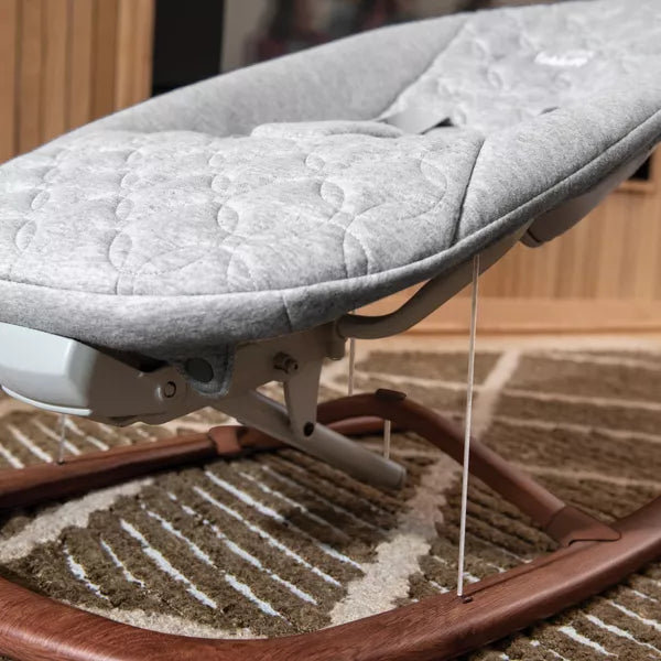 Baby bouncer with gray cushion on a carpeted floor