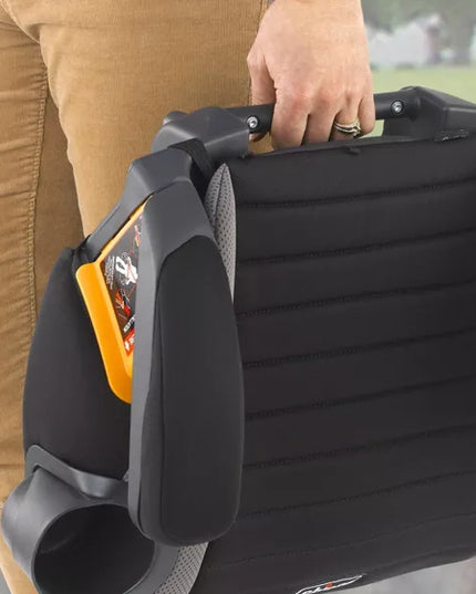 Person holding a black car seat with cup holder attachment outdoors.