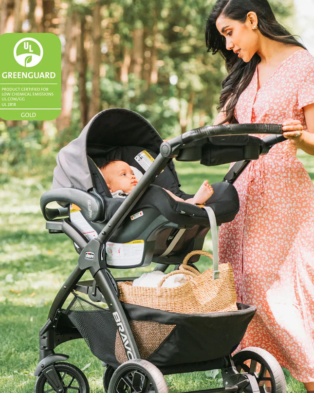 Woman pushing a stroller with a baby in a park, featuring the Greenguard Gold certification logo.