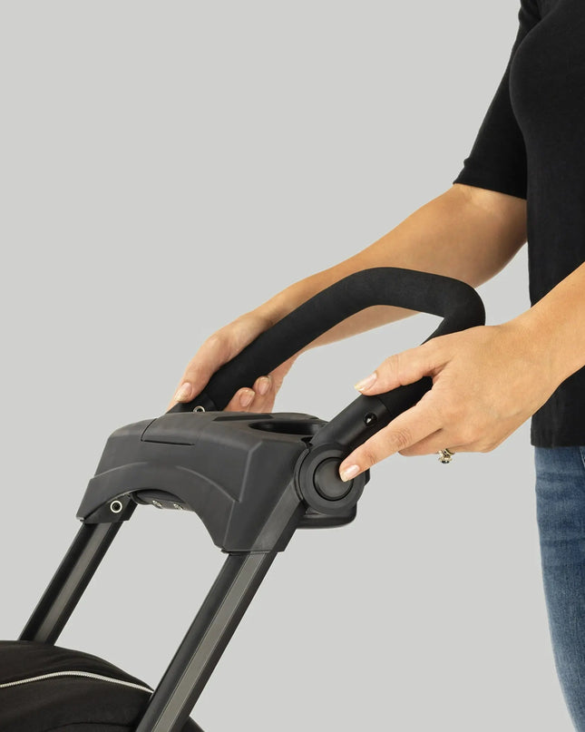 Person holding a black stroller handle against a gray background