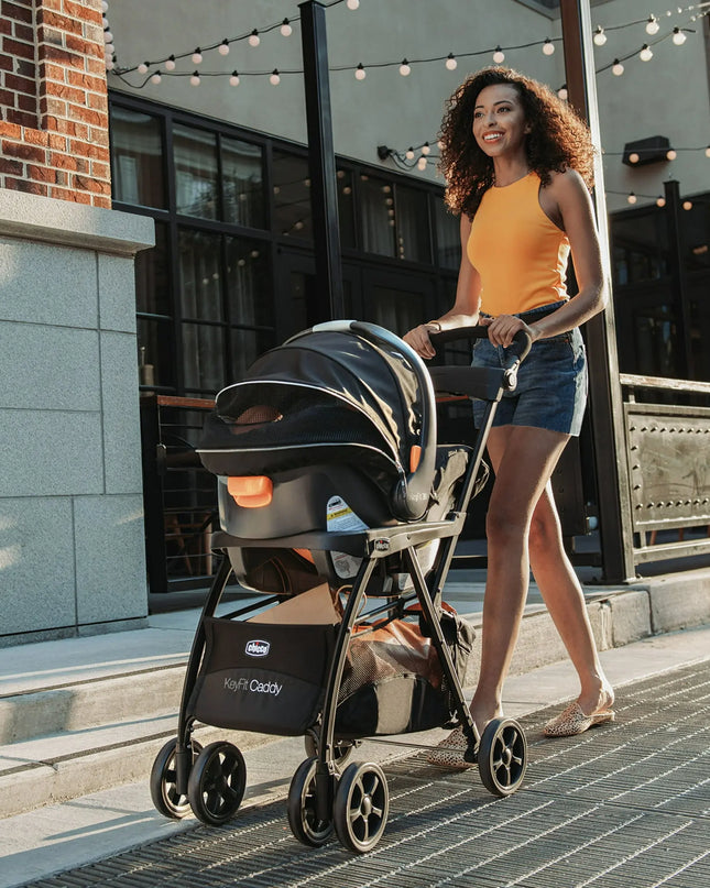 Woman pushing a stroller on a sidewalk with a building in the background