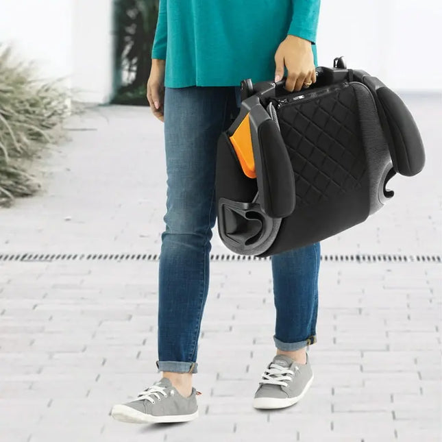 Person holding a black car seat cover with orange accents on a white brick background